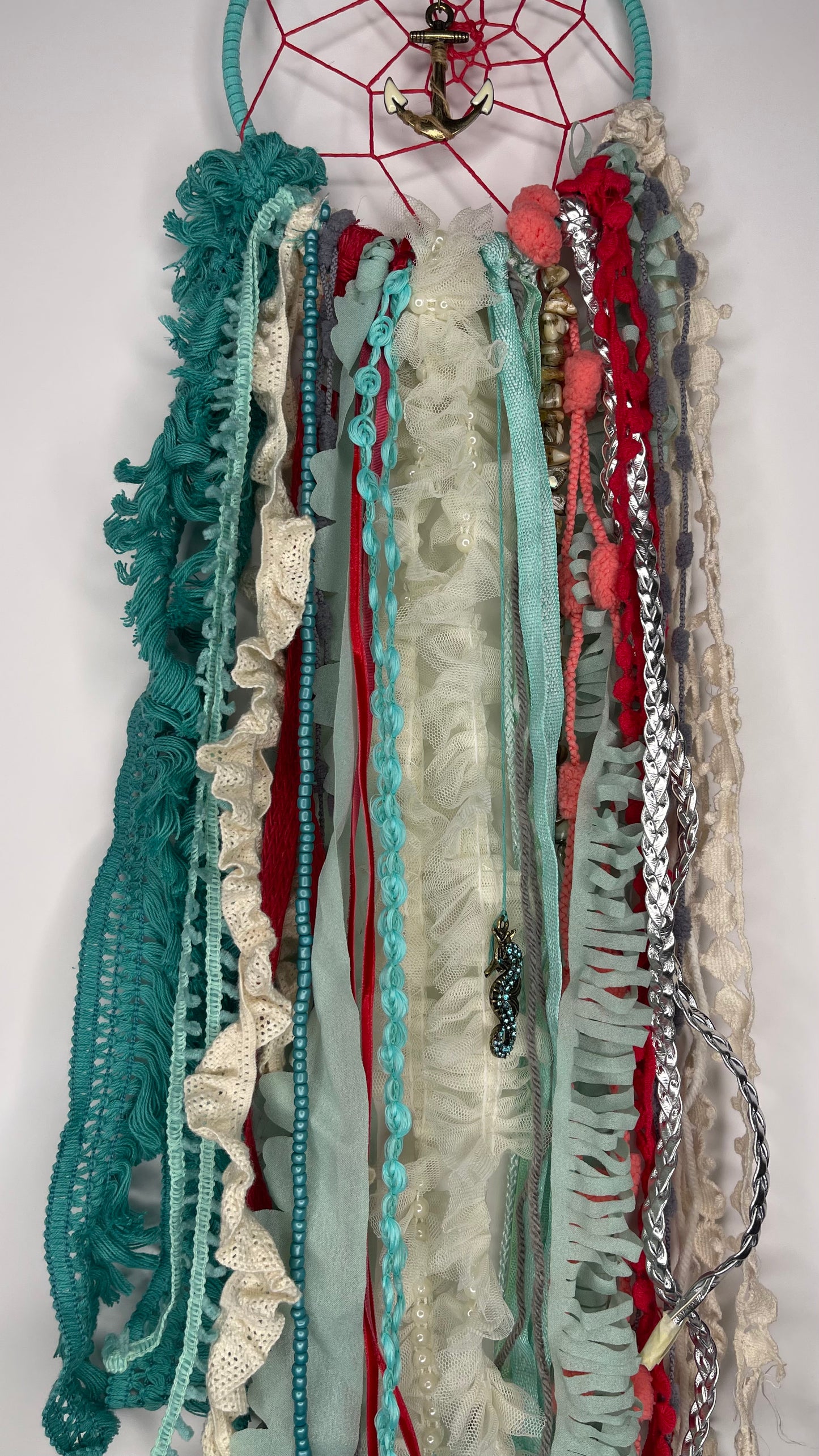 Decorative wall hanging with ribbons and a dreamcatcher on a white background