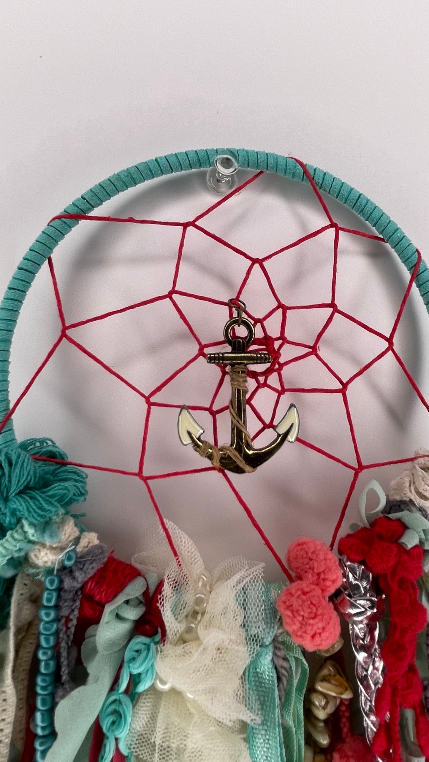 Dreamcatcher with anchor charm and colorful ribbons on a white background