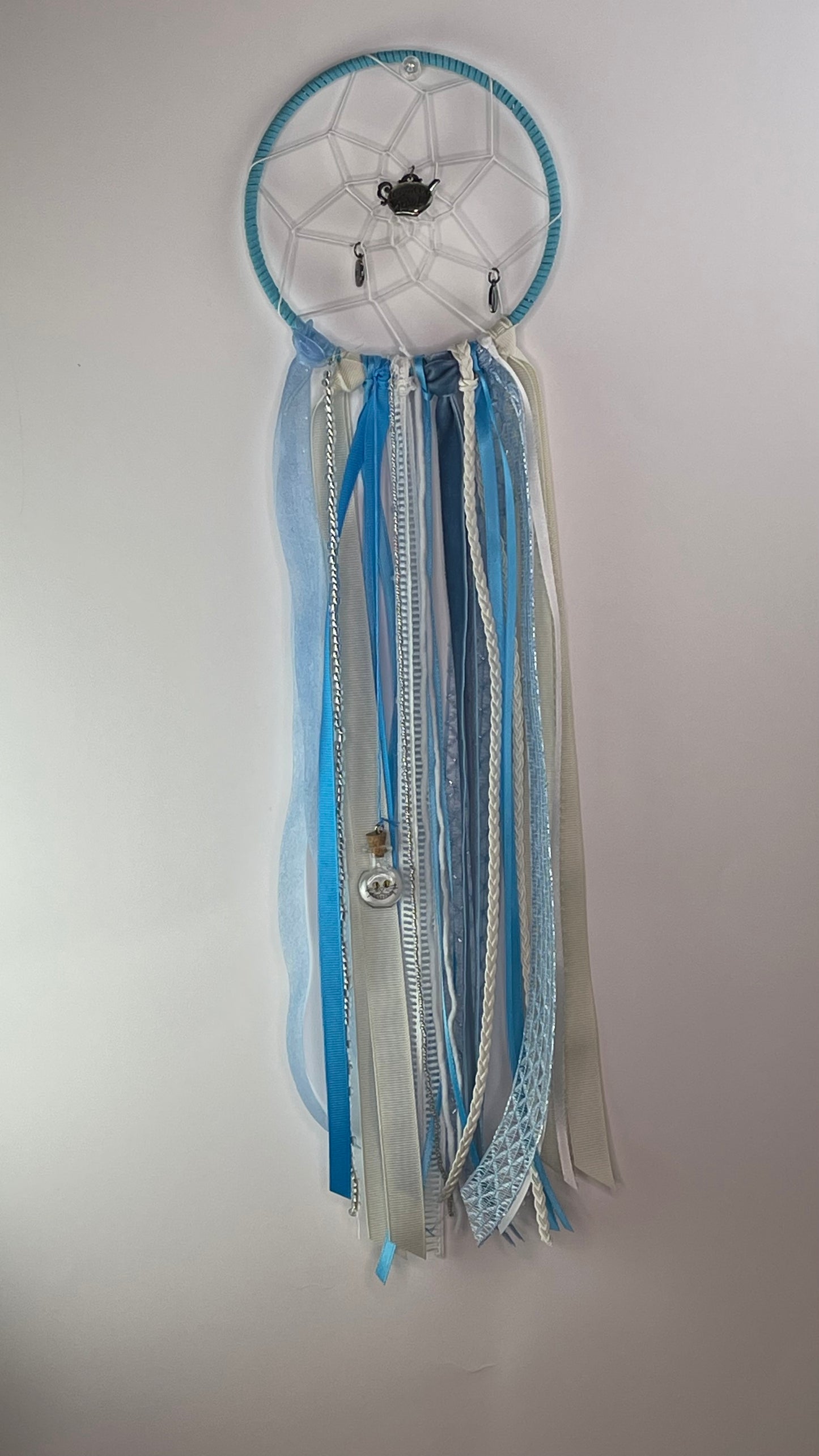 Dreamcatcher with blue and white ribbons on a plain background
