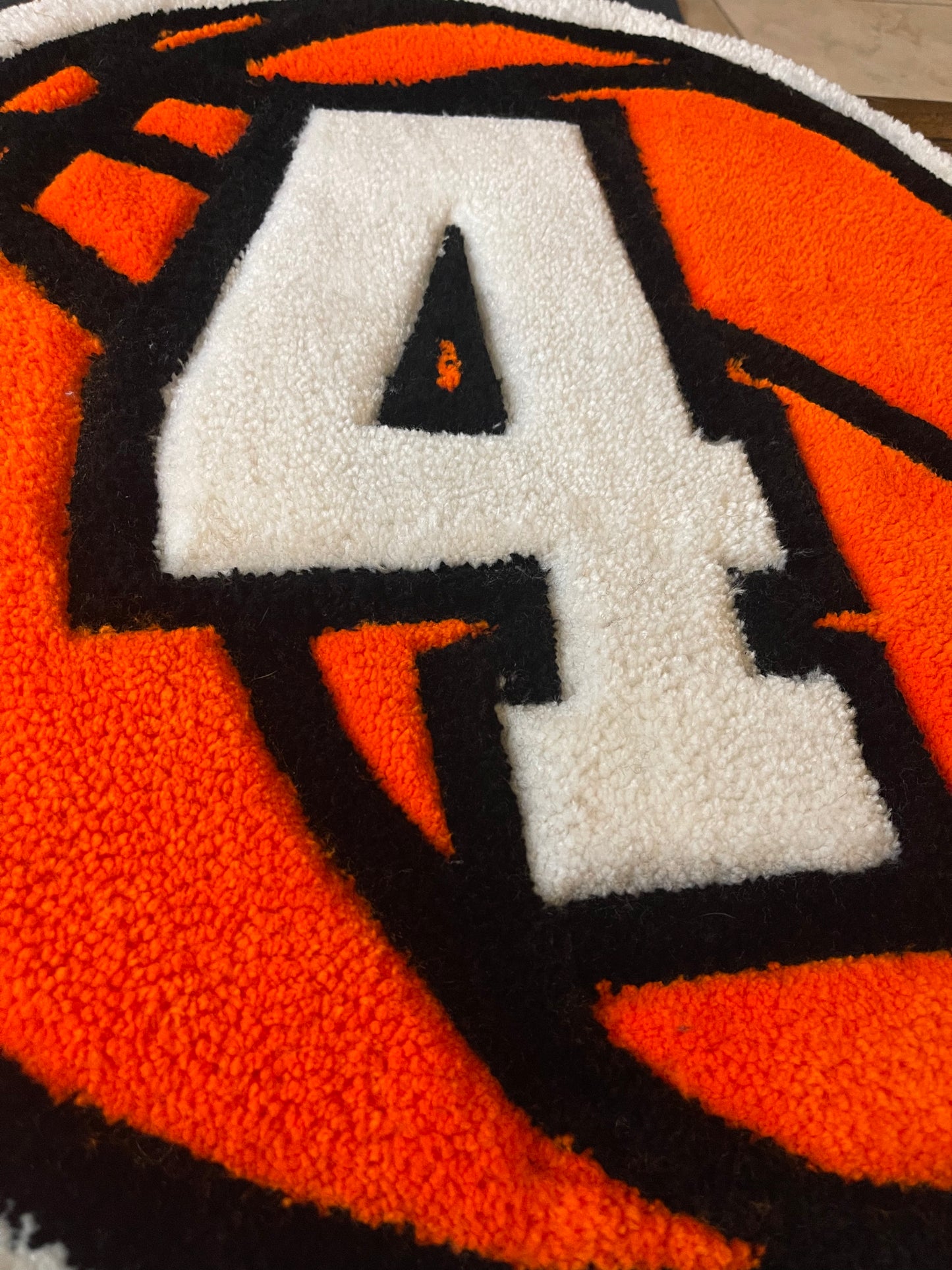 Close-up of a textured rug with a large white number '4' on an orange basketball background